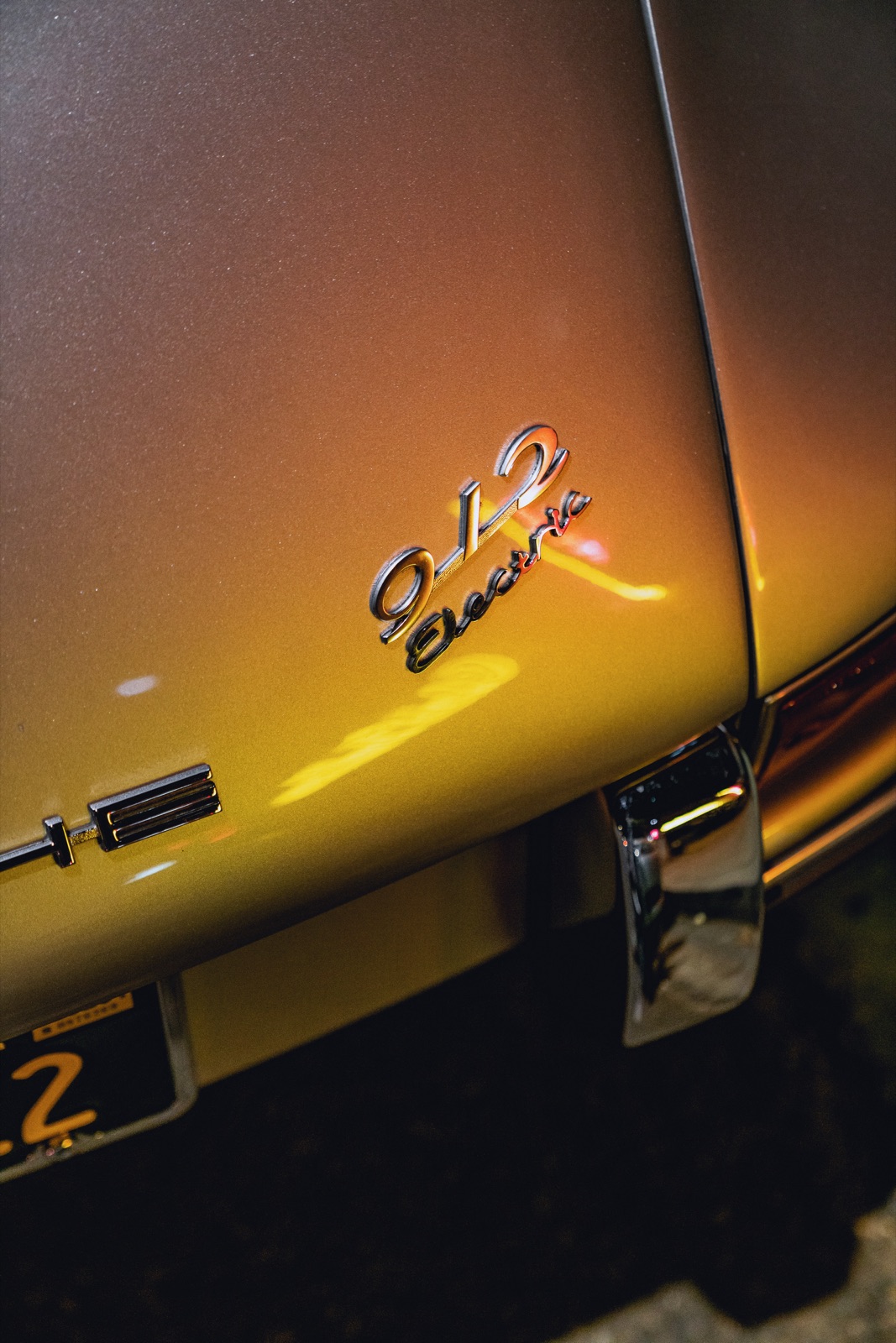 The &lsquo;912 Electric&rsquo; rear badge glowing gold at night