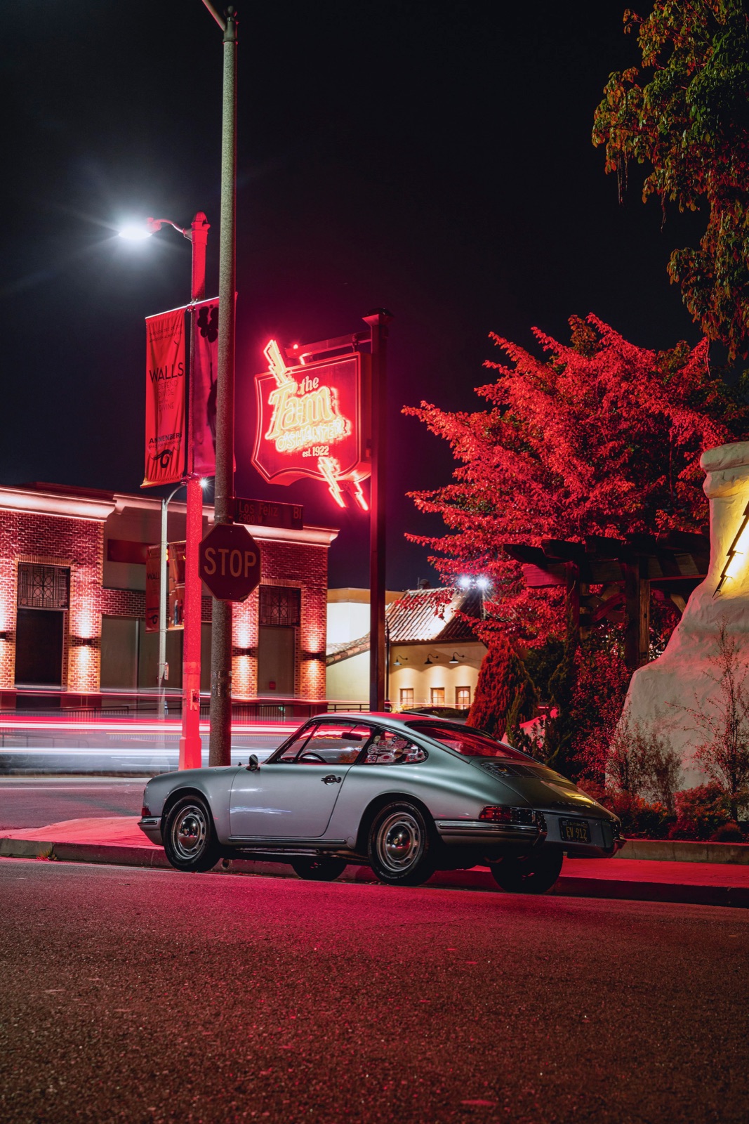The 912 at night on a neon-lit street, traffic light-trails behind